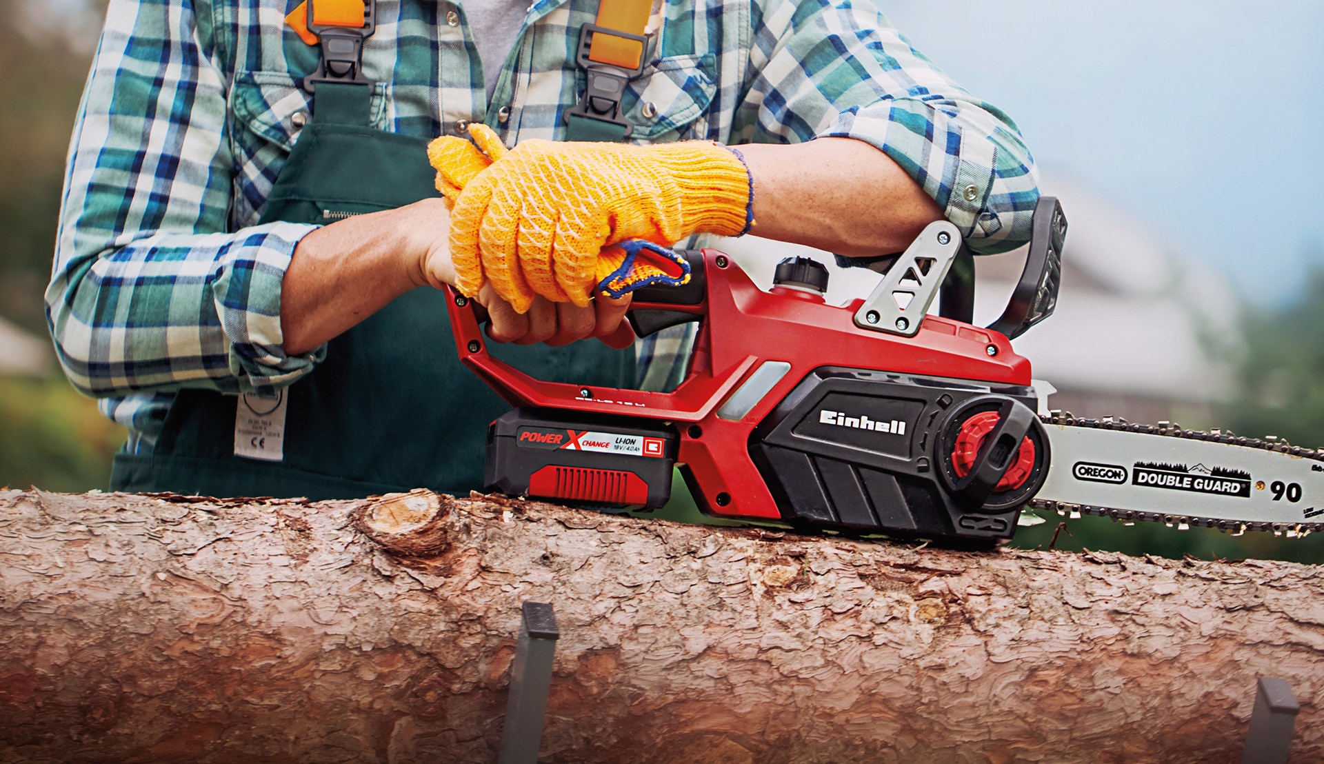 A man places a chainsaw on a tree trunk