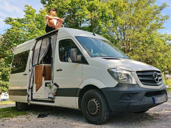 man sits on the roof of the converted van