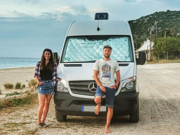 man and woman leaning against car on beach