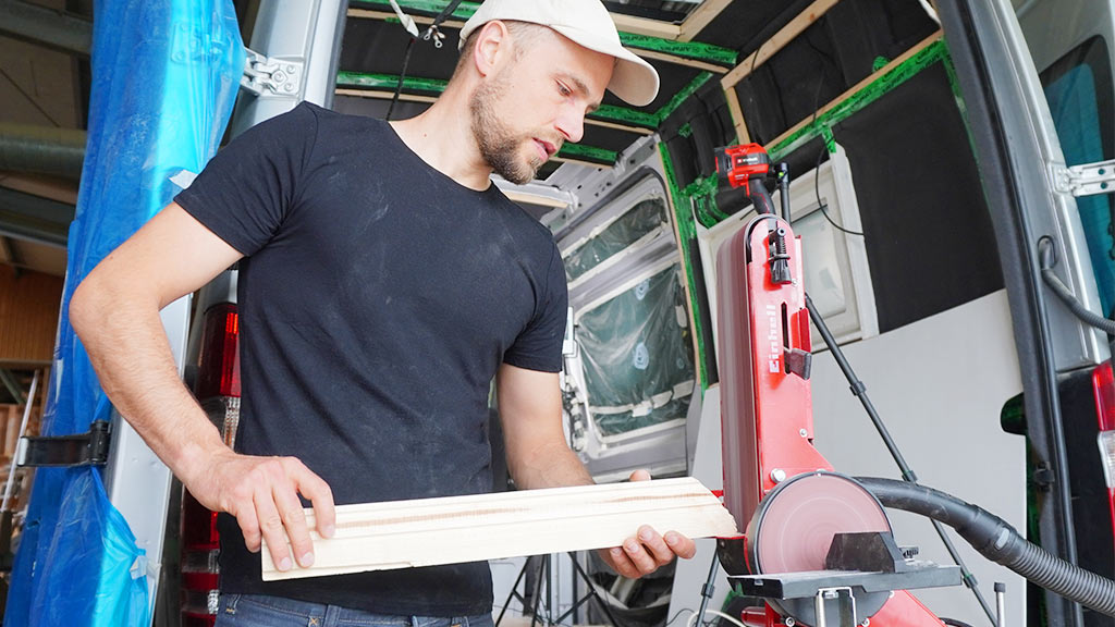 a man sands a wooden beam