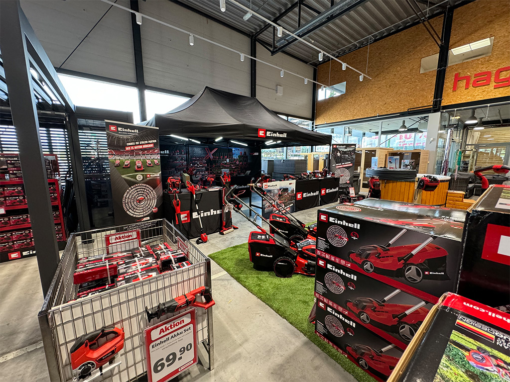 A closer view of Einhell's indoor promotional setup featuring tools, lawn mowers, and branded displays.